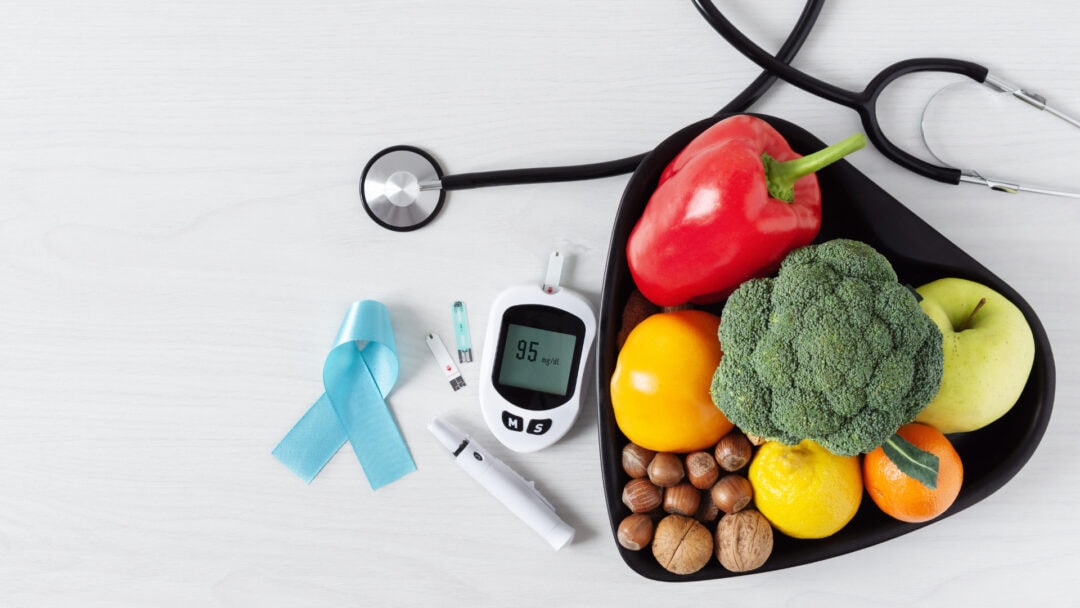 Stethoscope, blood glucose monitor, insulin pen, and healthy foods for diabetes care.