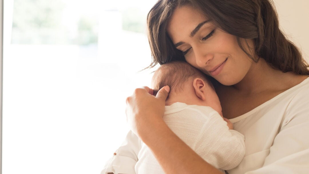 Mother holding her newborn baby close with love and care.