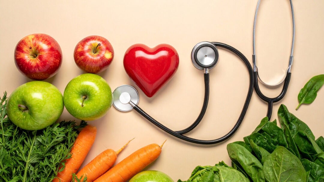 Stethoscope with apples, carrots, and leafy greens emphasizing nutritious choices for heart and diabetes management.