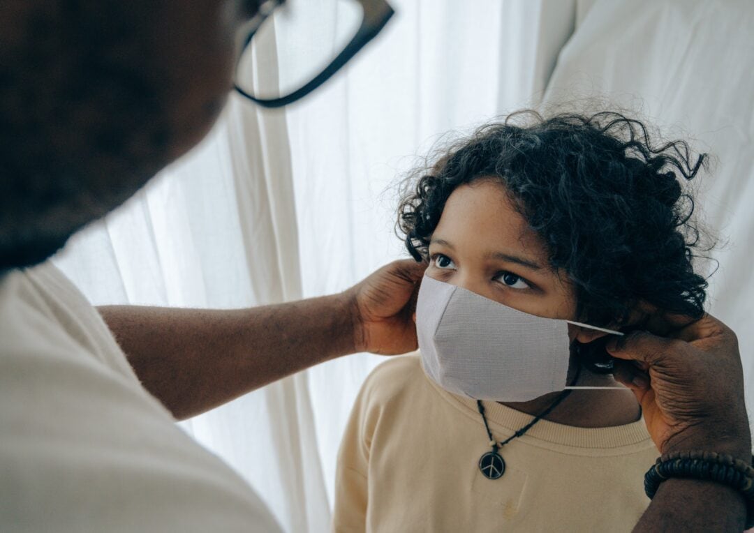 A man putting on a face mask to a child.