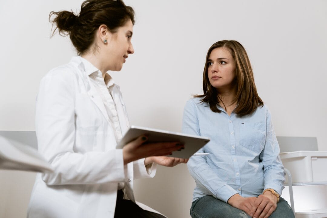 A woman is talking to a doctor while sitting in a chair.